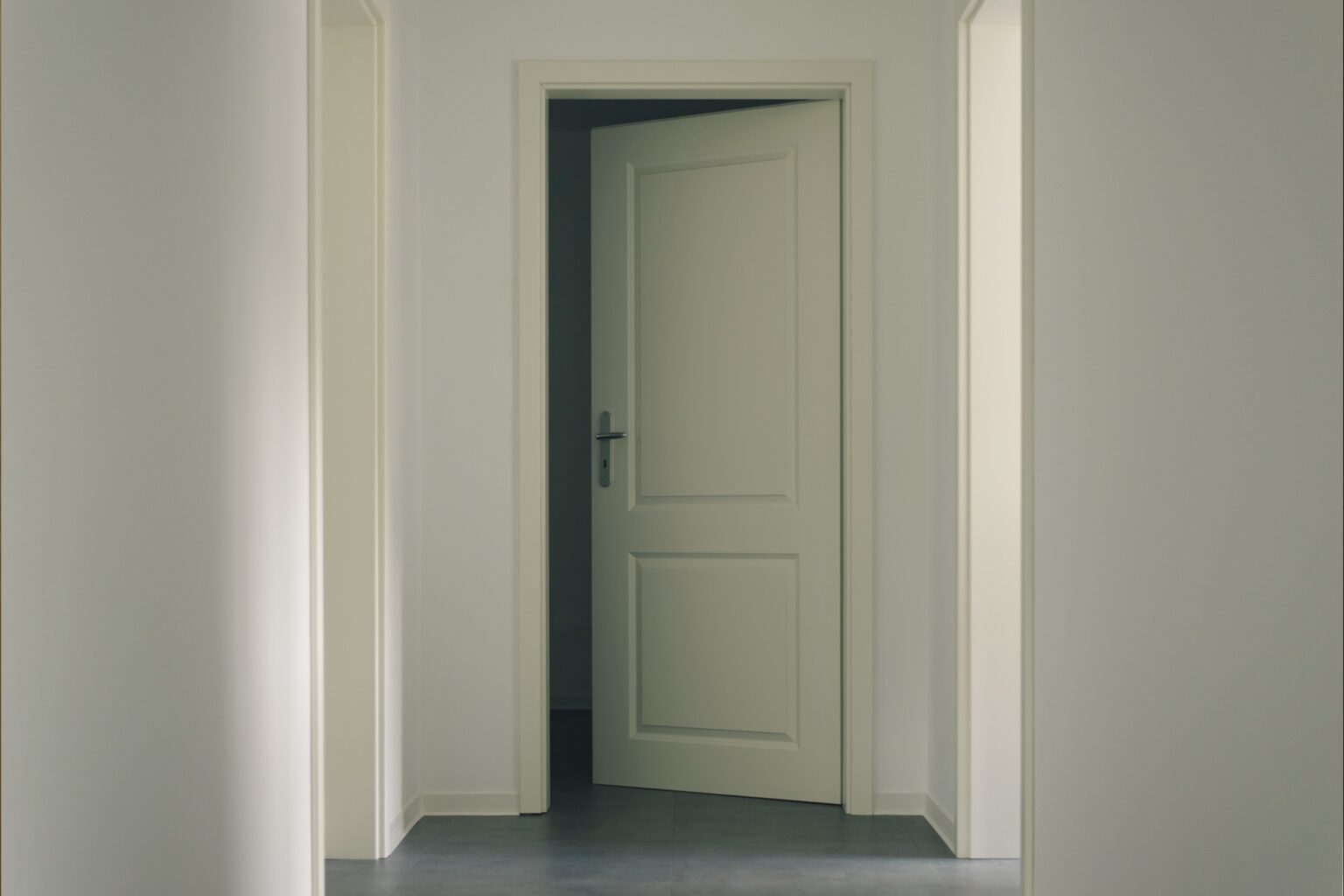 A white door in the middle of an empty room.