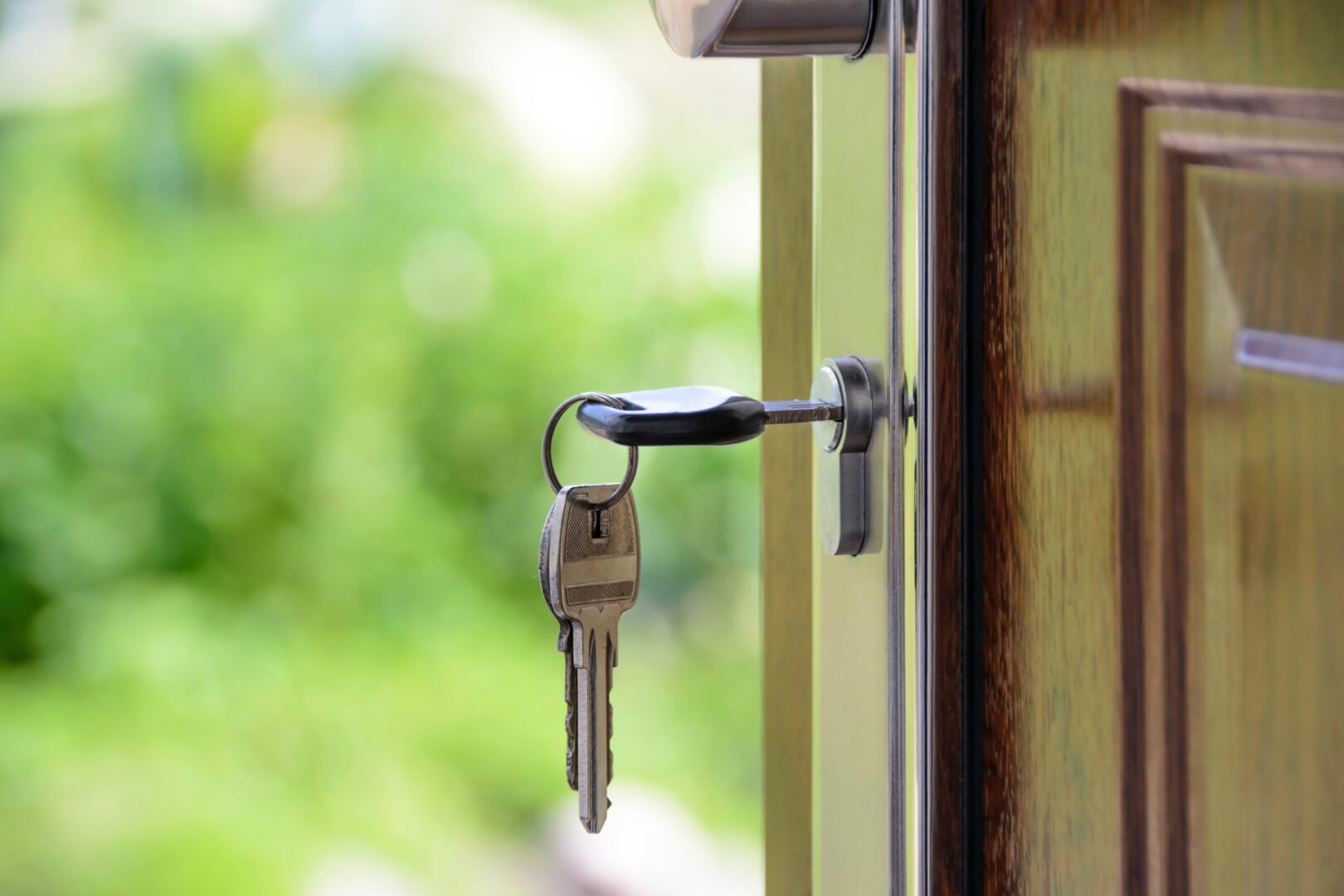 A bunch of keys hanging from the handle of a door.