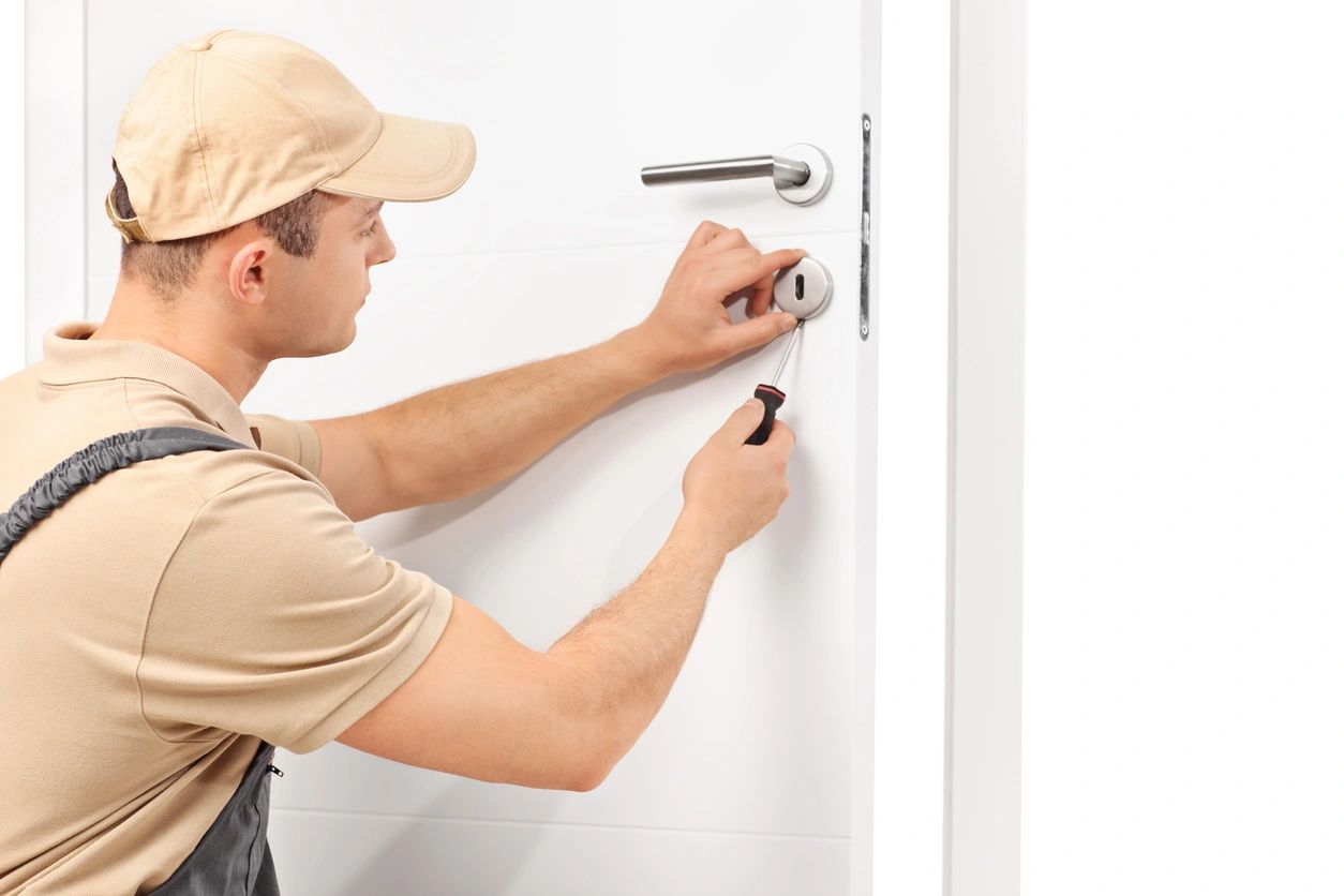 A man in tan shirt and hat painting a door.