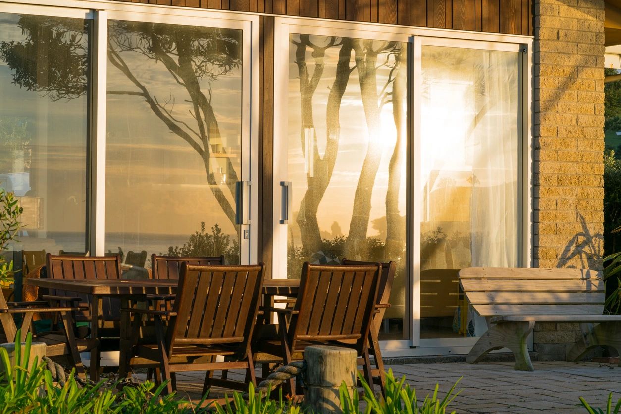 Two chairs are outside of a large glass door.